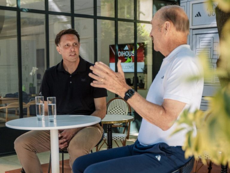 Zwei Männer im Gespräch an einem runden Tisch in einem adidas-Umfeld – professioneller Austausch und Beratung