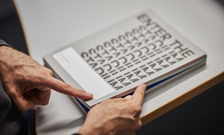 Hände halten ein Designbuch mit großer Typografie auf dem Cover – Storytelling- und Designkonzept für adidas Brand Flagship Stores in New York und London